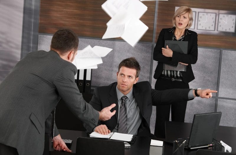 A man and woman in business suits arguing with another man due to being wrongfully terminated from their job